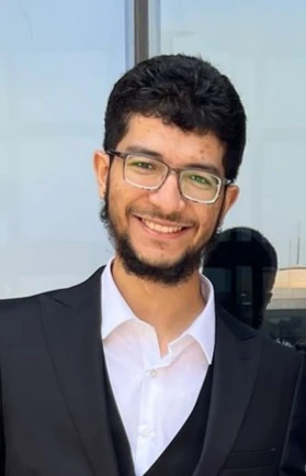 Ahmed Ehab, smiling, wearing glasses and a dark suit